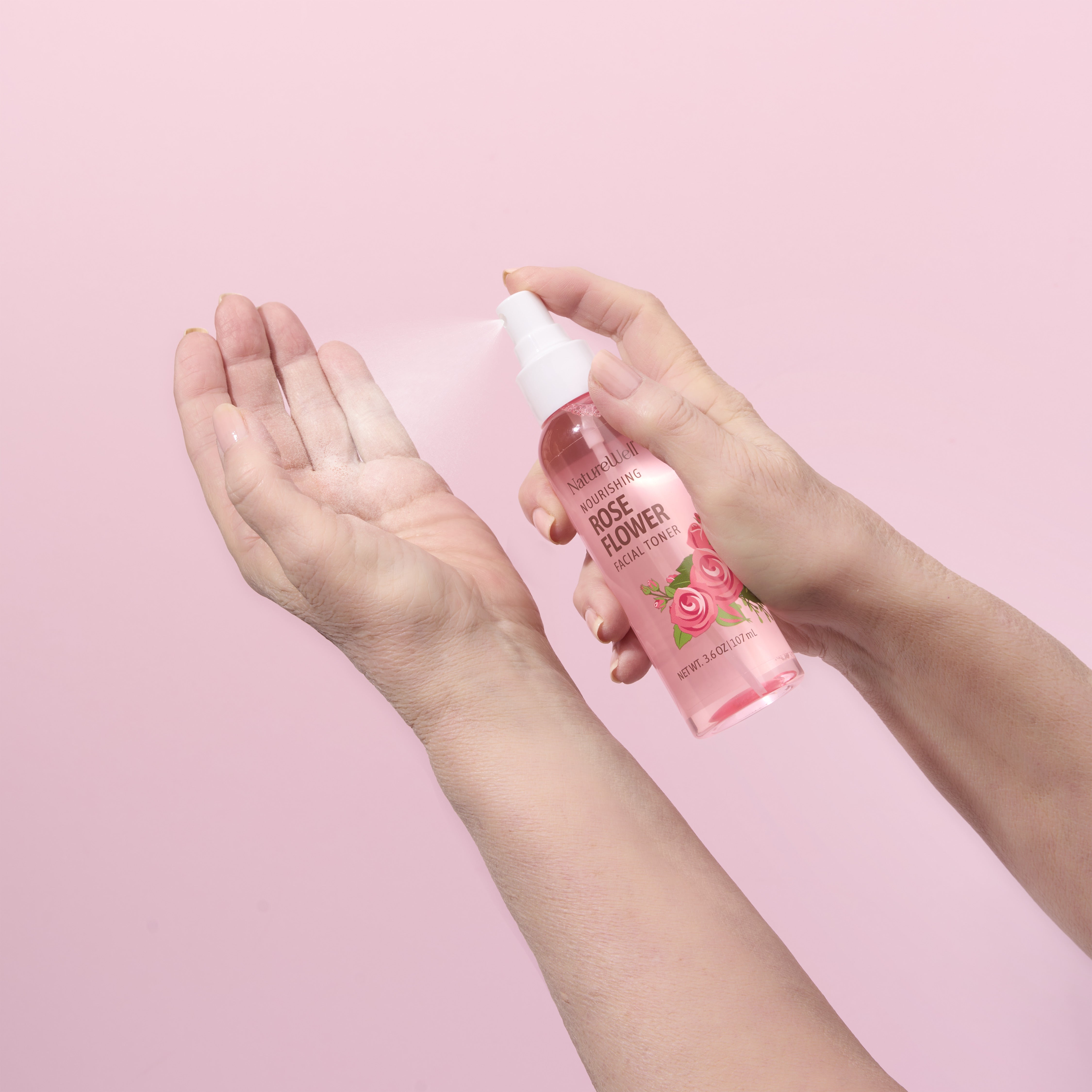 woman spraying rose flower facial toner onto hand with product misting from spray nozzle