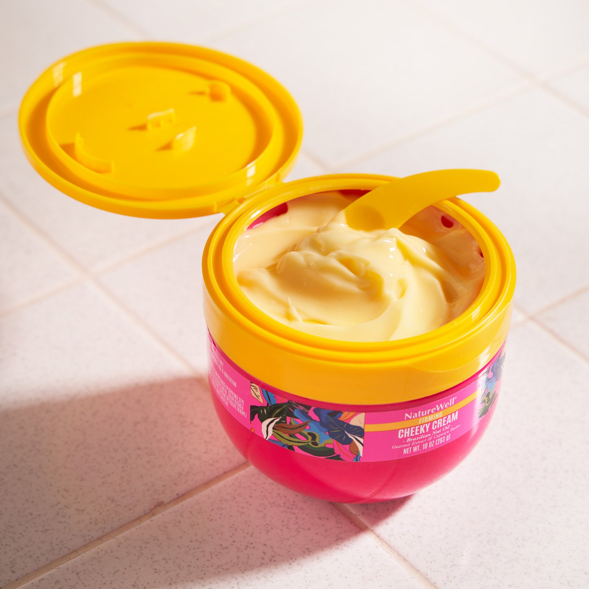 Open jar of hydrating body cream with a spoon scooping out a small amount