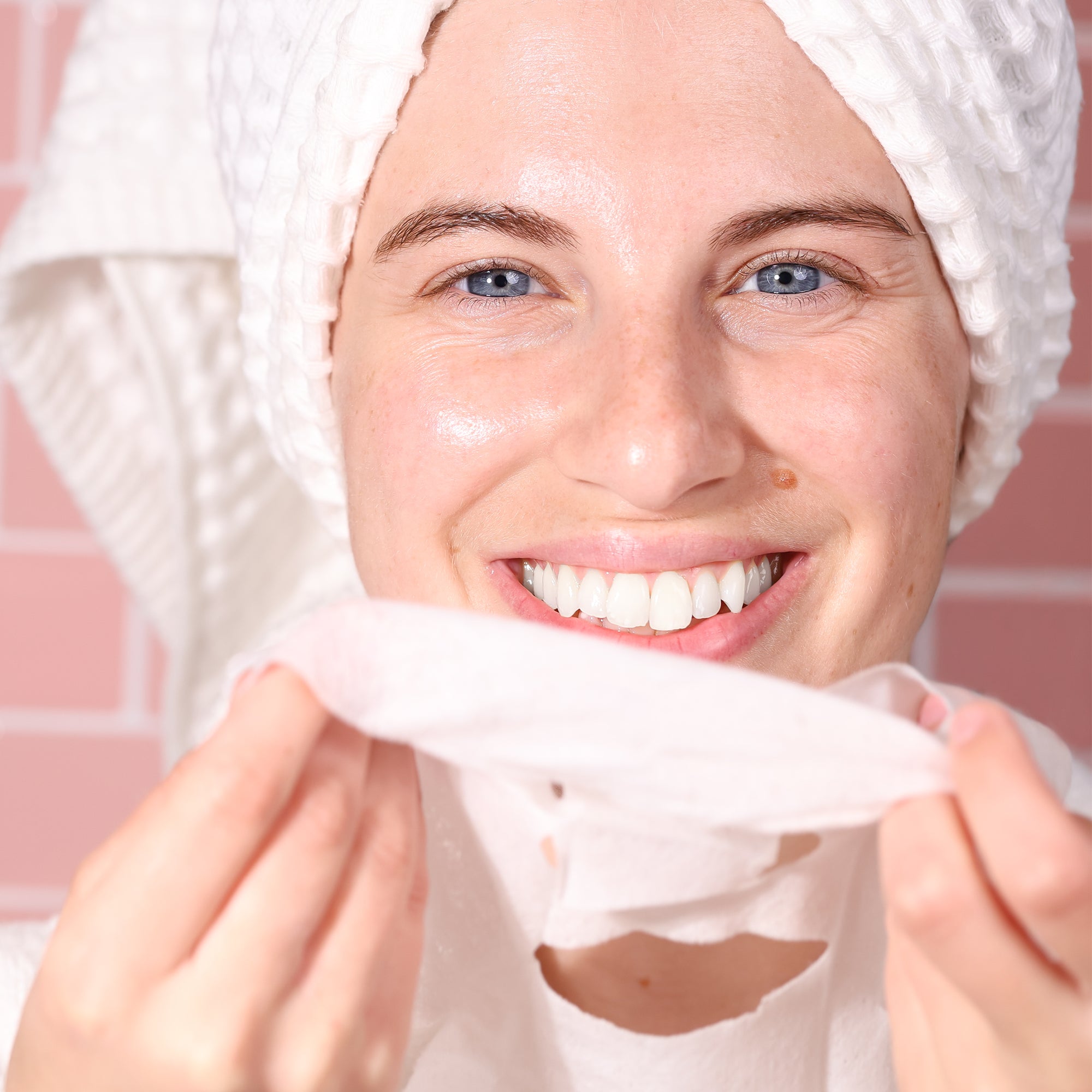 woman smiling and preparing sheet mask to be applied to her clean face