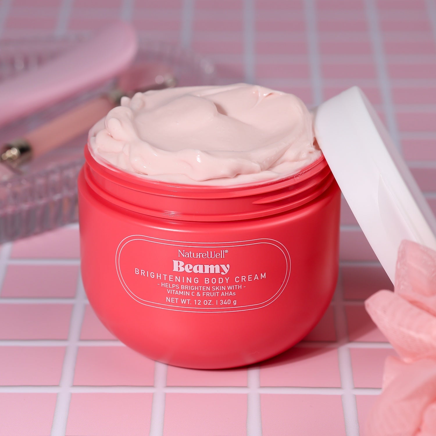 Open jar of NatureWell Beamy Brightening Body Cream on a pink tiled counter
