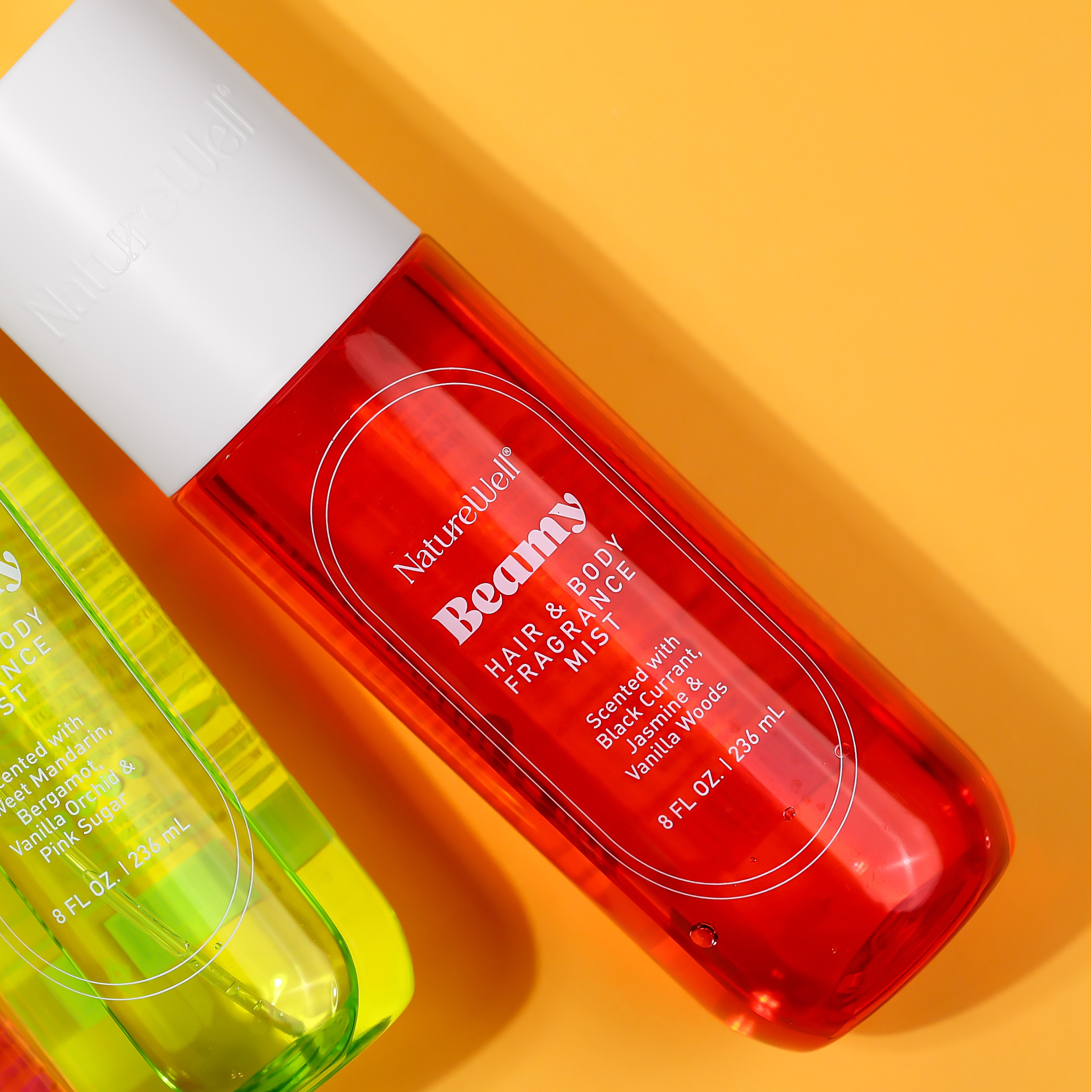 Bottle of NatureWell Beamy Hair and Body Fragrance Mist on an orange background