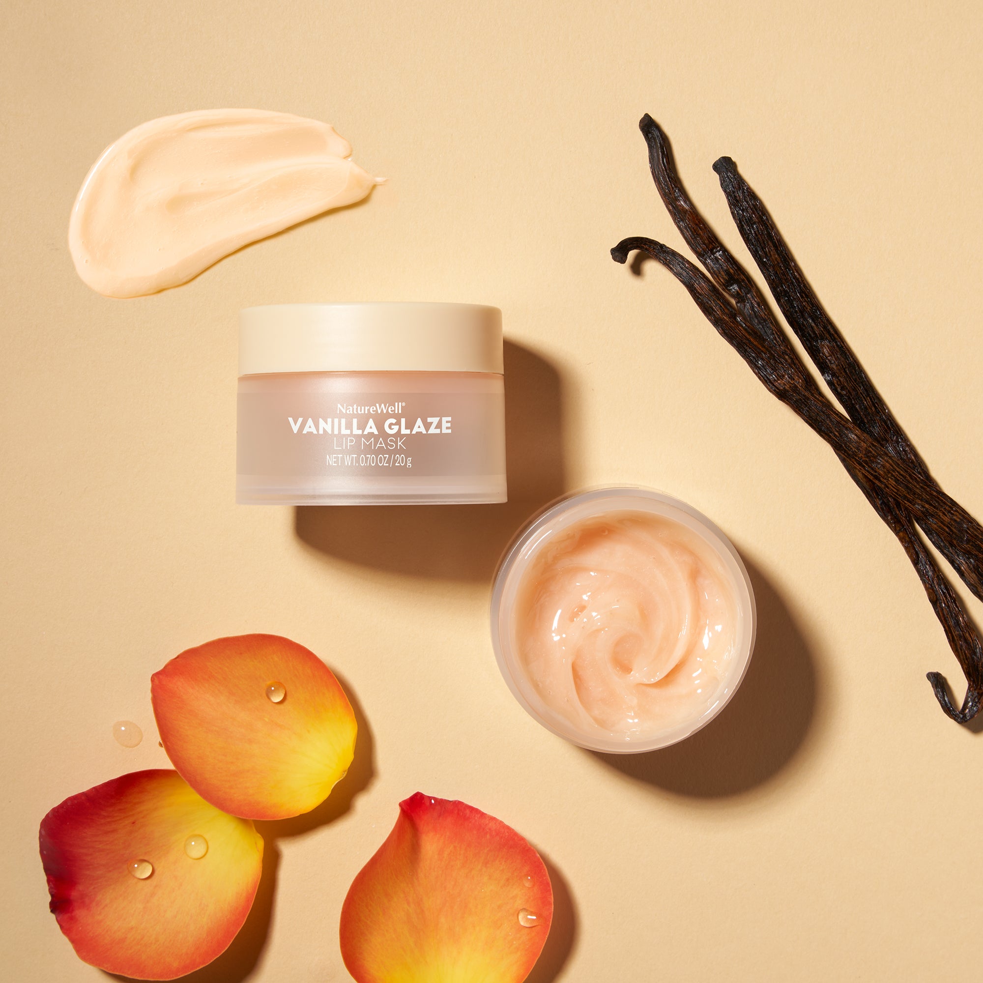 Jar of NatureWell Vanilla Glaze Lip Mask beside vanilla pods and flower petals on a beige background
