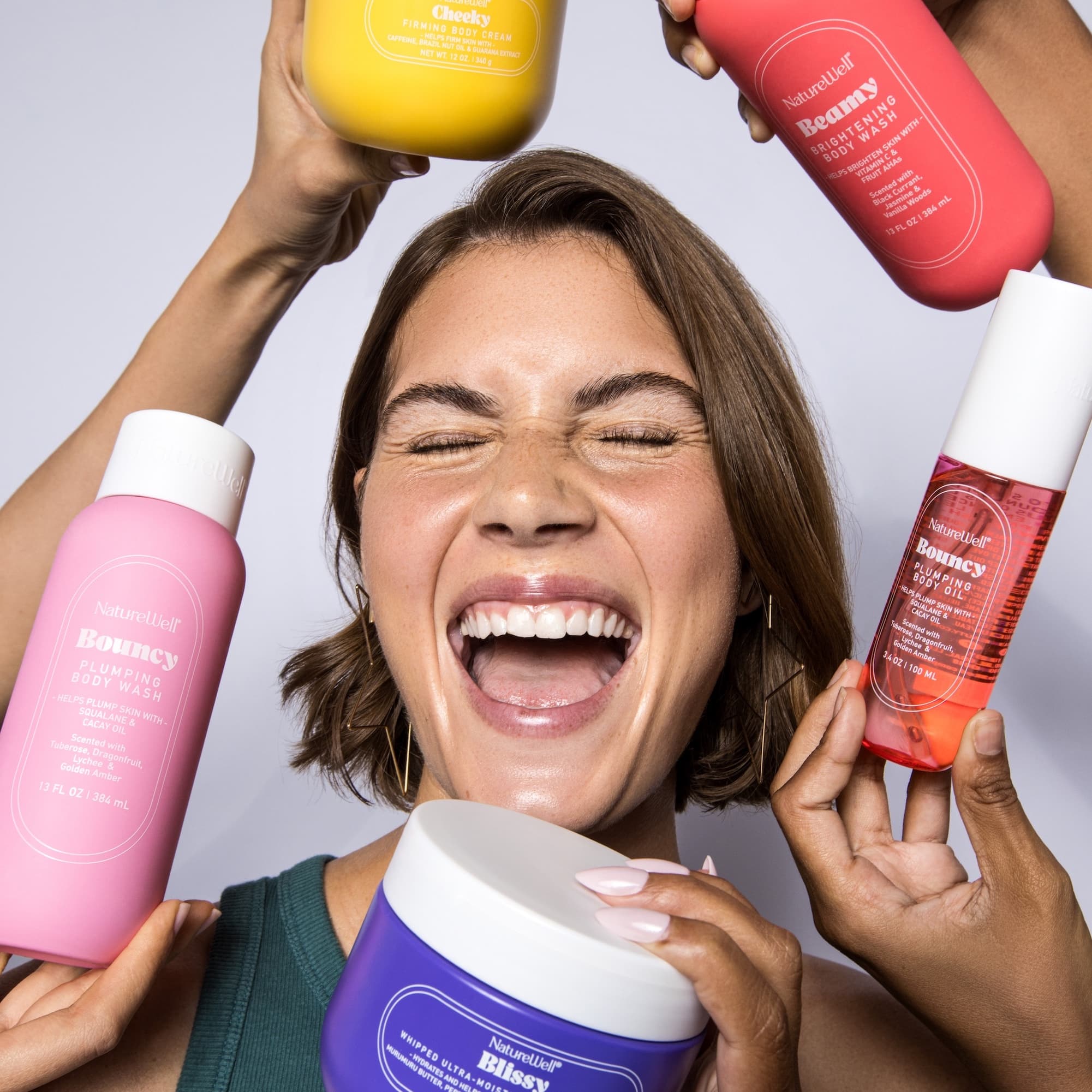 Woman smiling holding a variety of NatureWell body products near her face