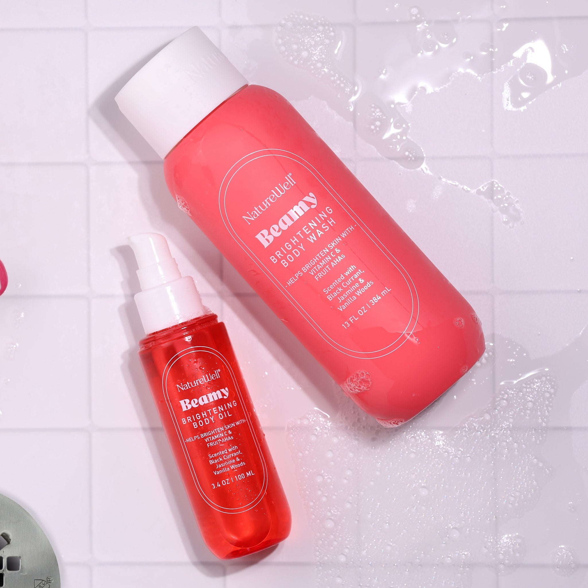 Bottles of NatureWell Body Wash and Body Oil on a white tile background