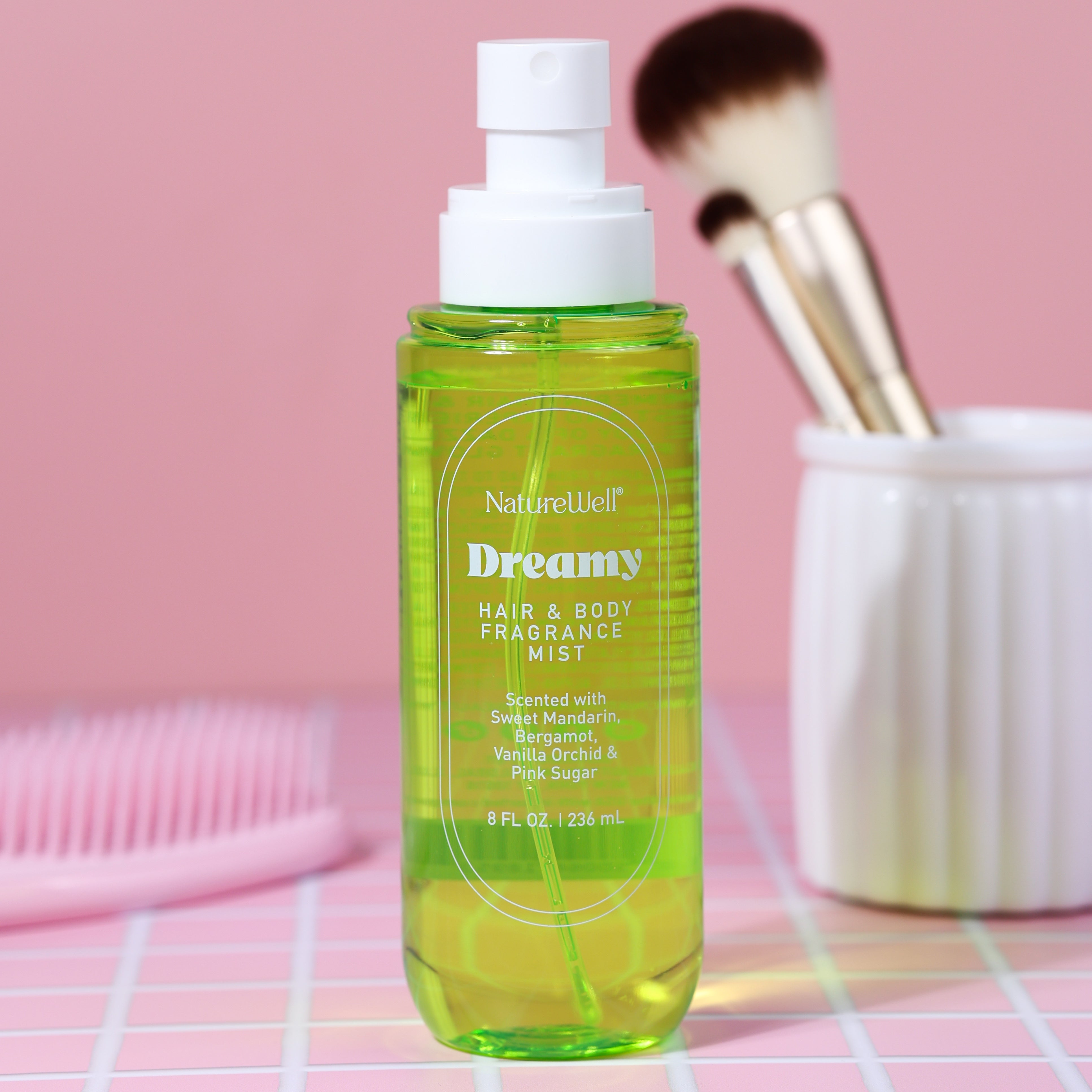 Bottle of NatureWell Dreamy Hair & Body Fragrance Mist on a pink countertop