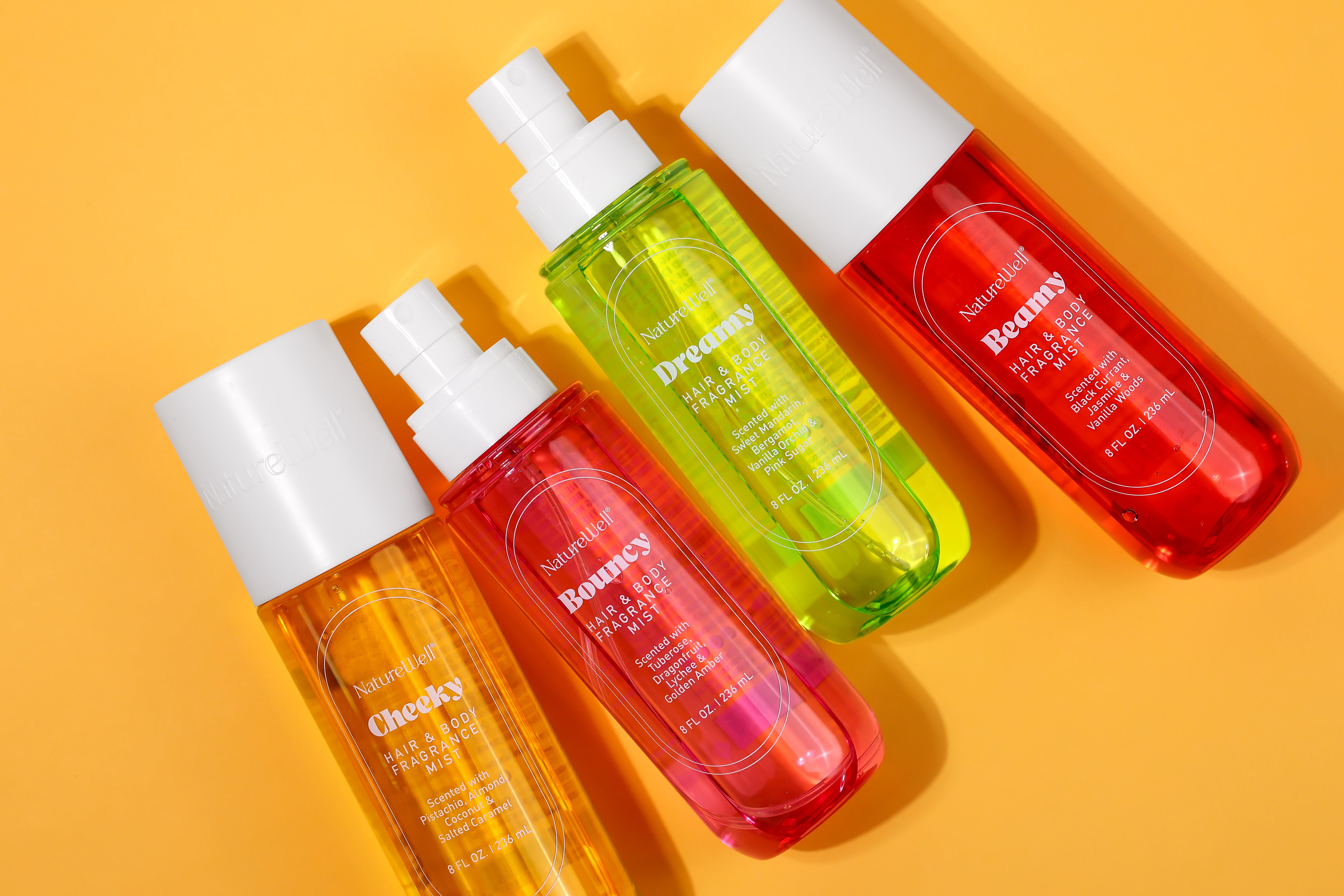 Colorful assortment of 4 bottles of NatureWell Hair and Body Fragrance Mist in Cheeky, Bouncy, Dreamy, and Beamy scents