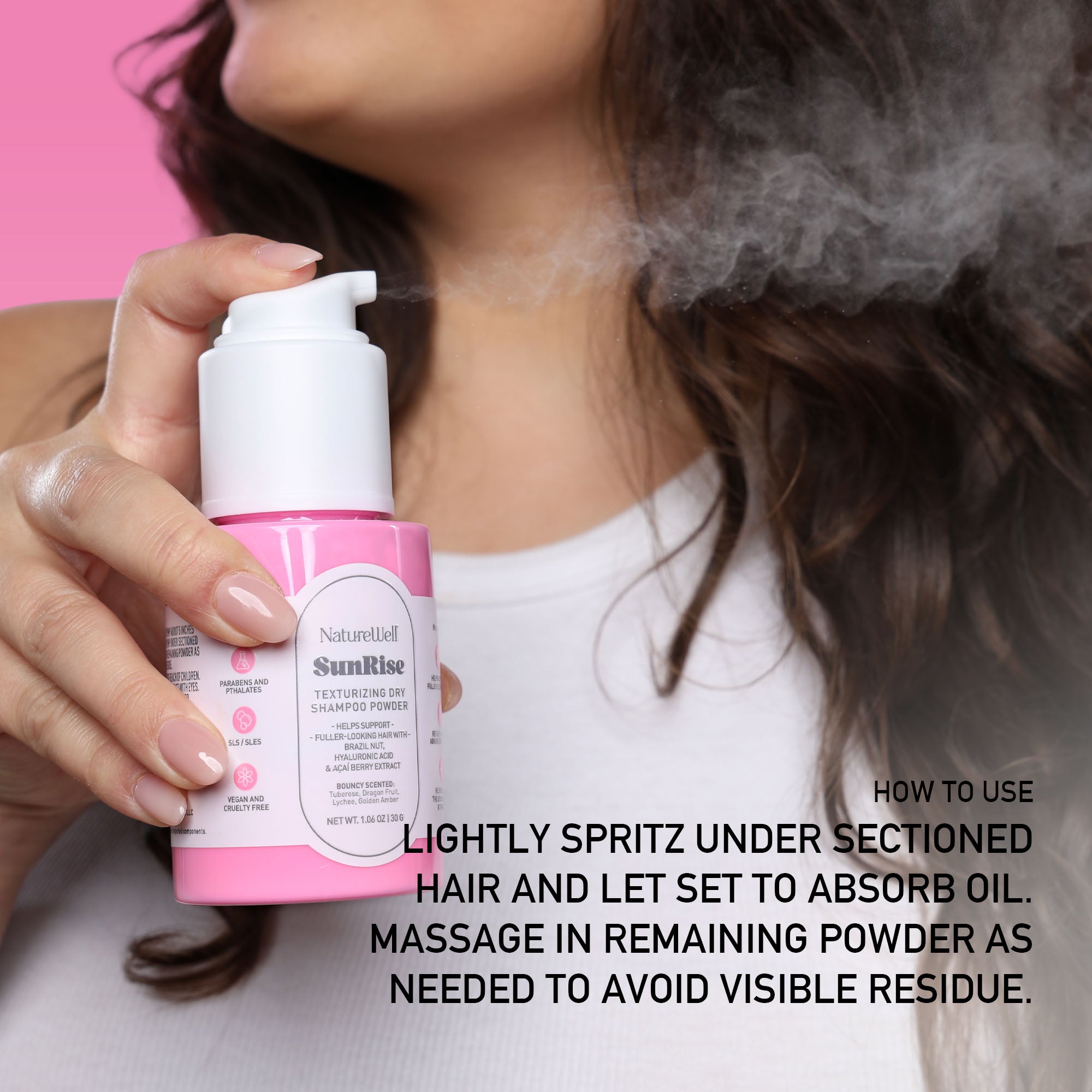 Woman applying NatureWell SunRise Dry Shampoo against a pink background with text overlay