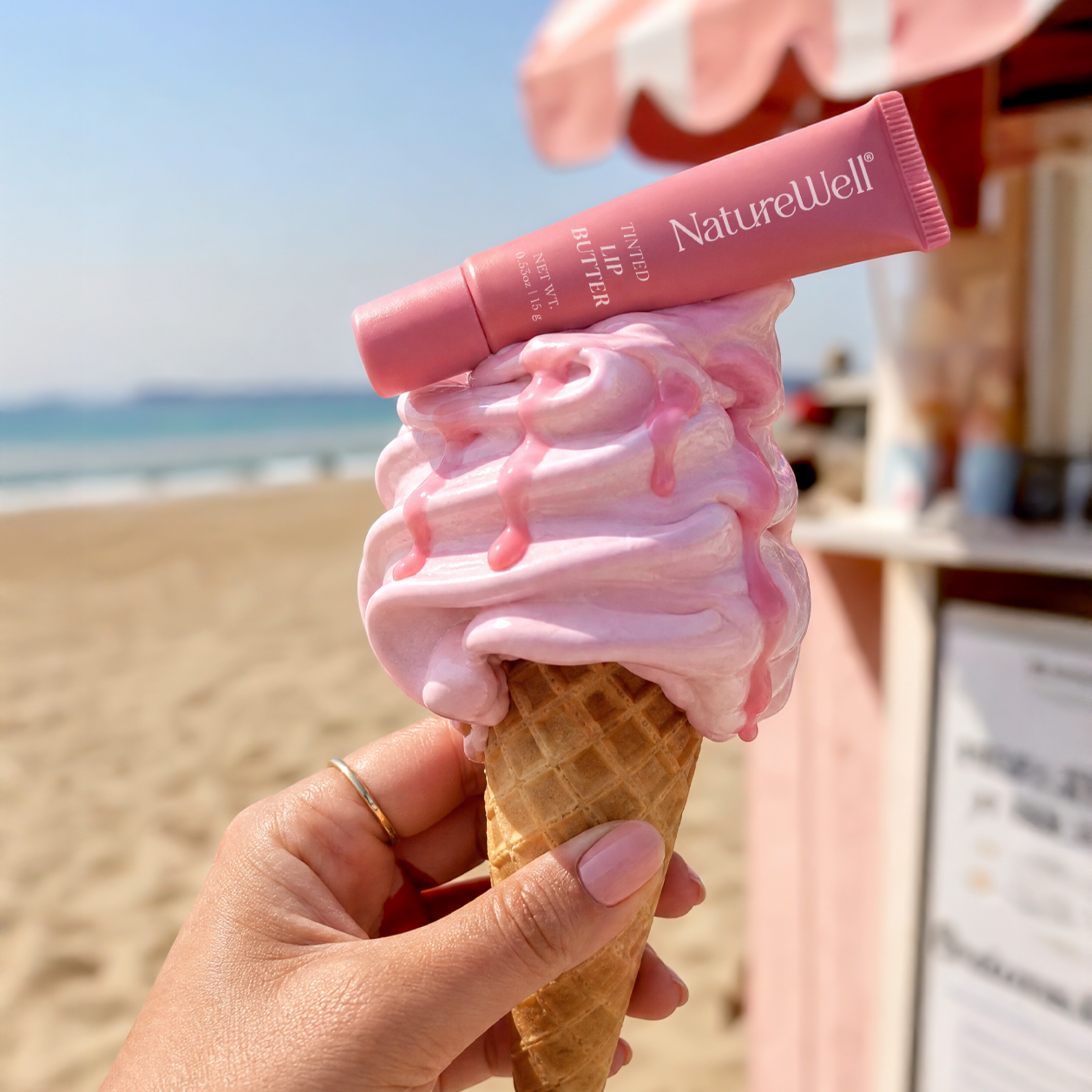 Tube of NatureWell Pink Velvet Lip Butter on top of a scoop of ice cream white a natural background
