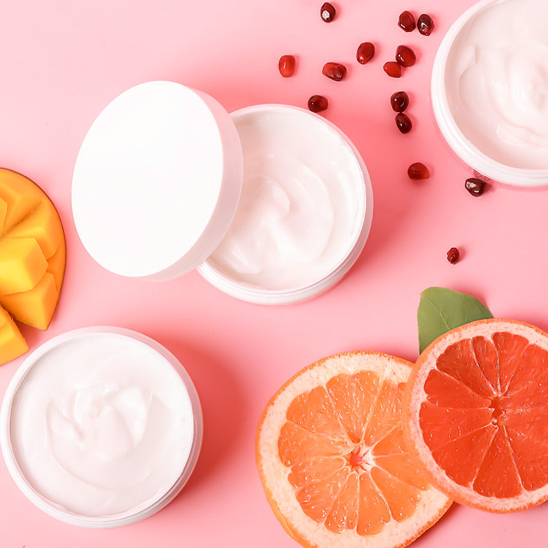 3 open jars of scented moisturizing creams with grapefruit, pomegranate, and mango fruit