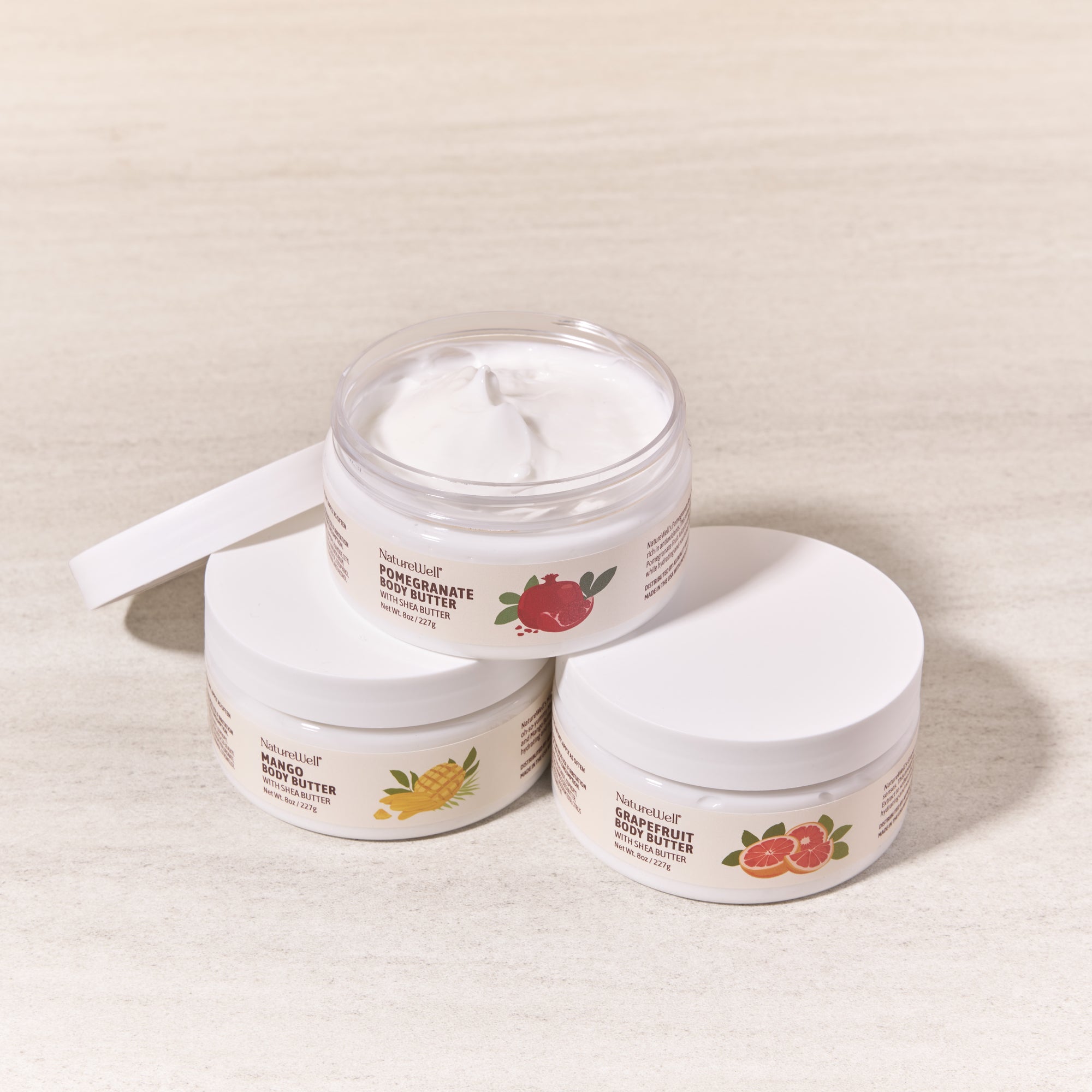 3 jars of scented shea butter body creams with the lid removed from 1 jar