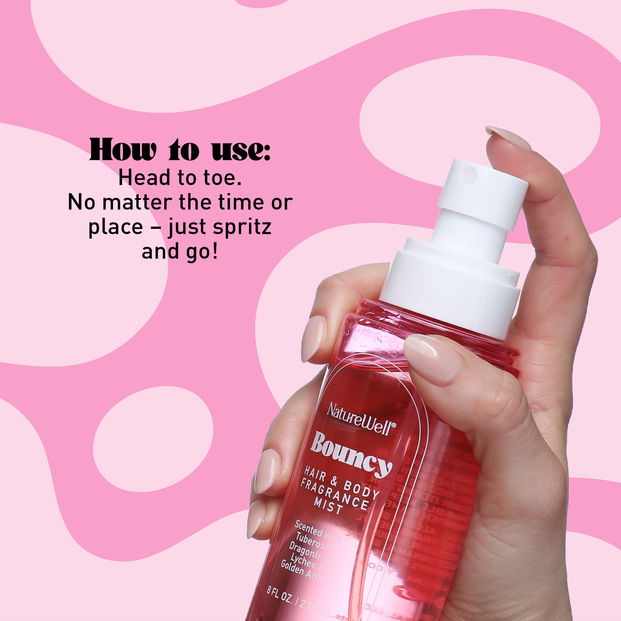 Woman spritzing product from NatureWell Bouncy Hair & Body Fragrance Mist against a pink background