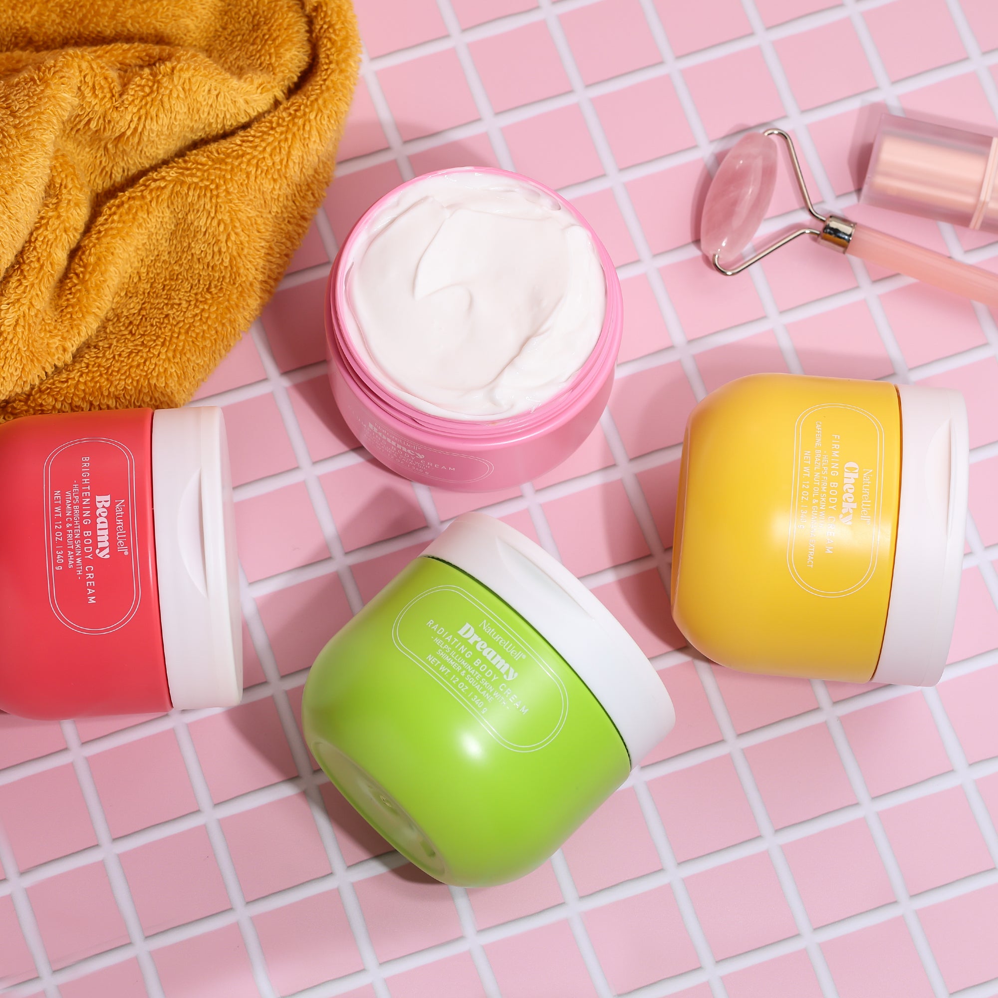 Assortment of 4 jars of NatureWell Body Creams on a pink tile countertop