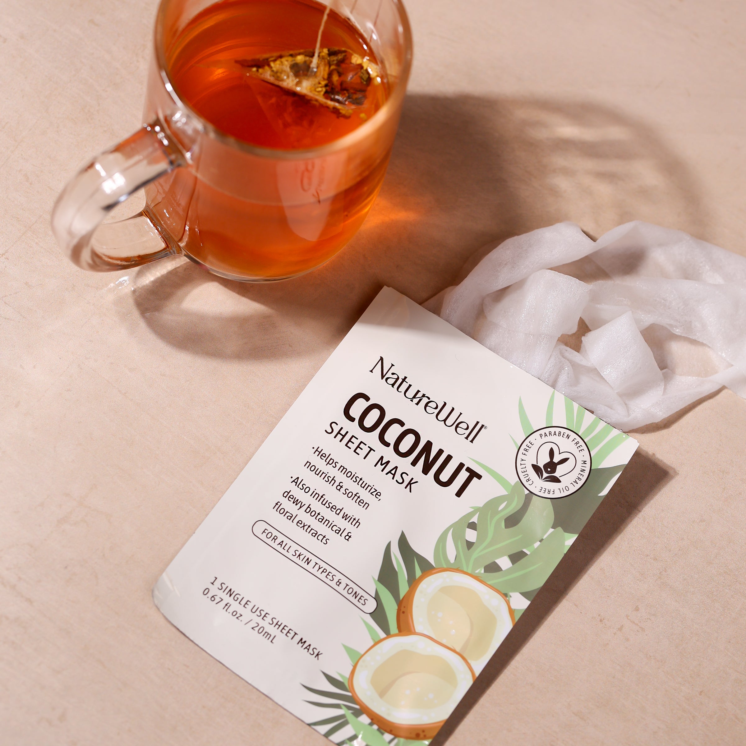 an open pack of moisturizing coconut sheet mask next to a mug of tea