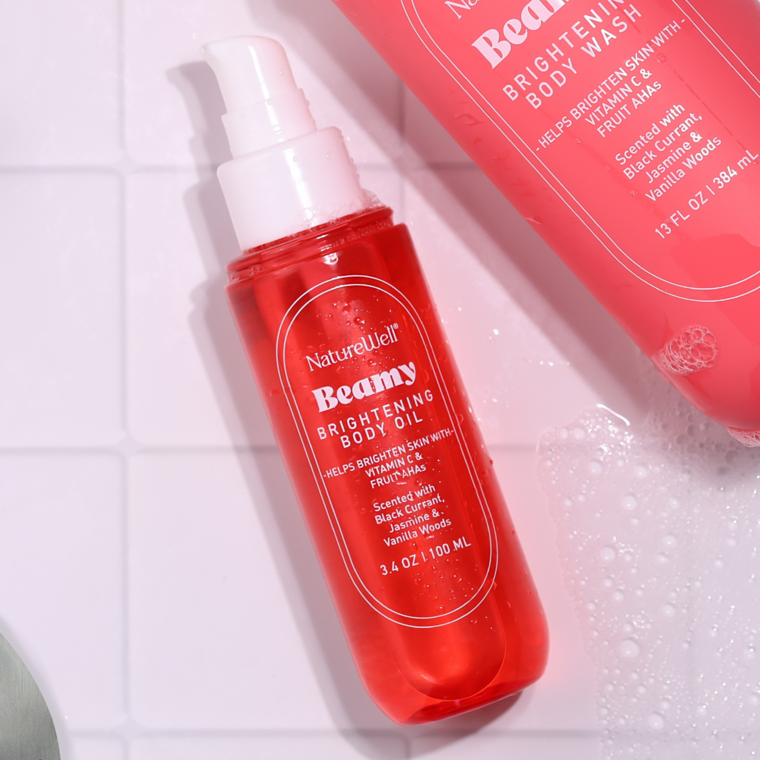 Bottle of NatureWell Beamy Brightening Body Oil on a white tile background