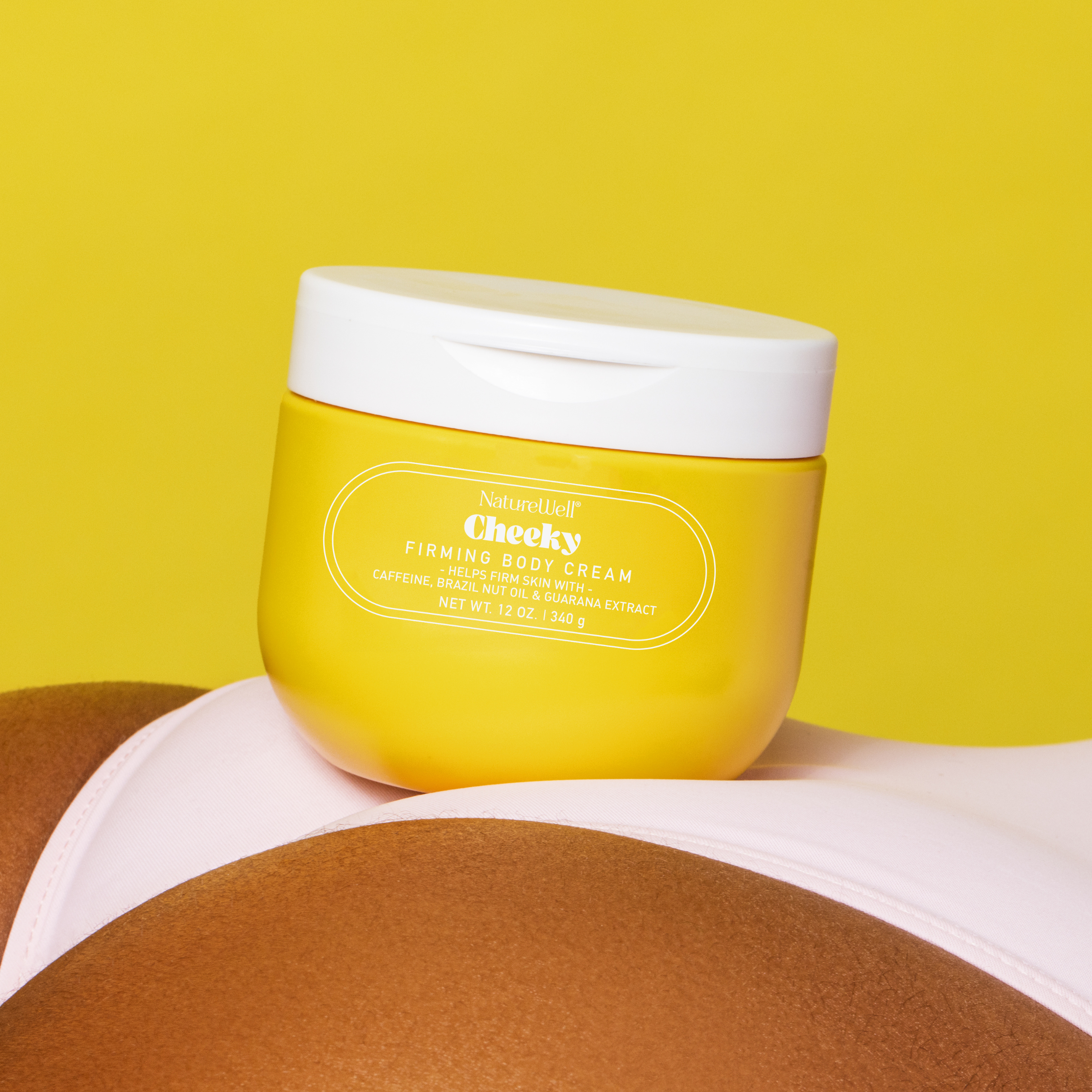 Jar of NatureWell Cheeky Firming Body Cream resting on top of a woman's back