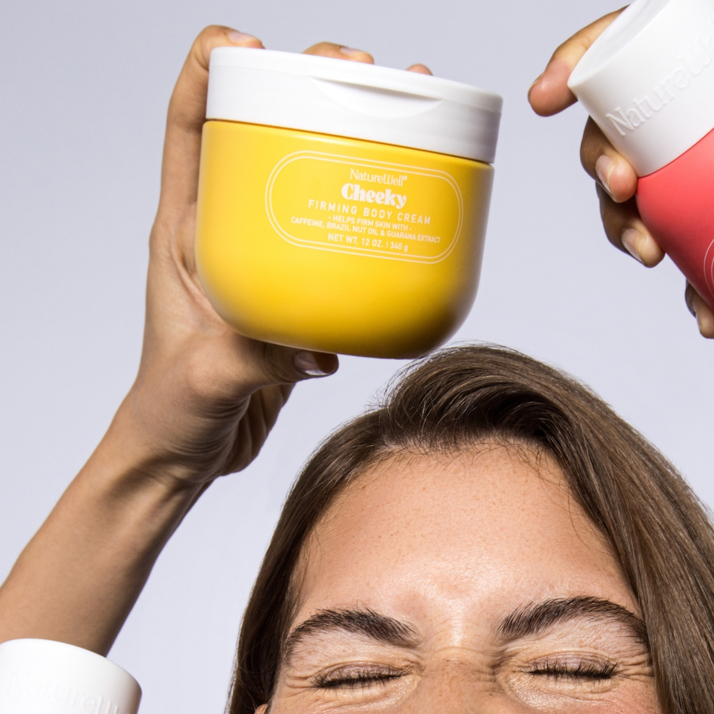 Woman holding a jar of NatureWell Cheeky Firming Body Cream over her head