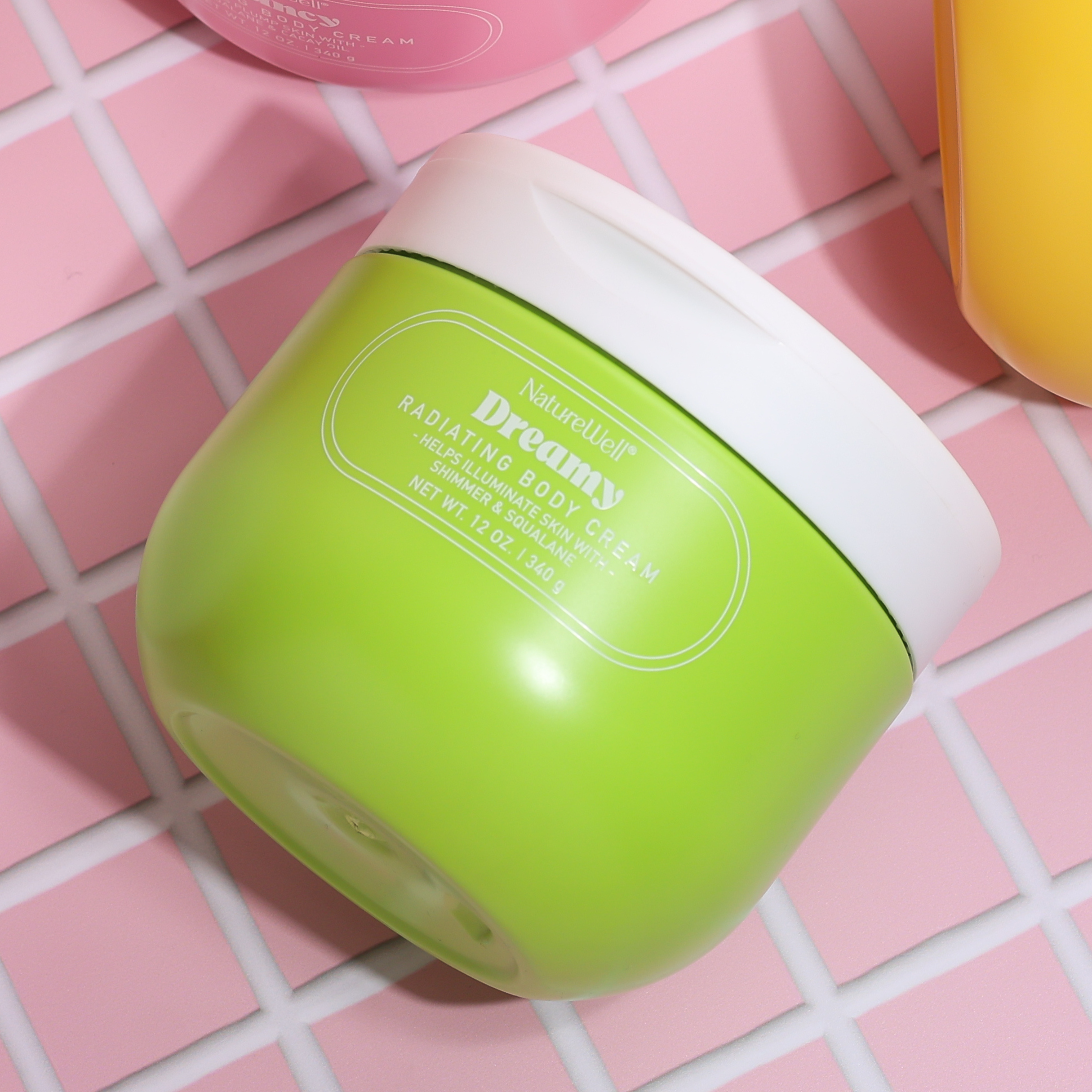 Jar of NatureWell Dreamy Radiating Body Cream on a pink tile background
