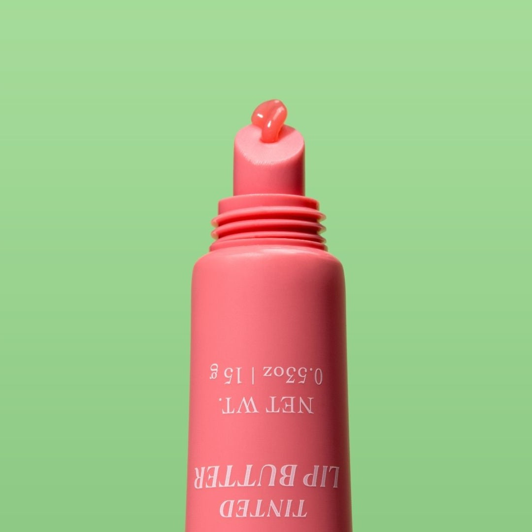 Pink tube of NatureWell Tinted Lip Butter on a green background