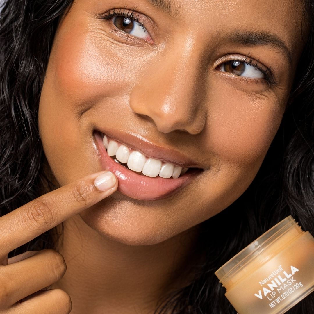 Woman holding a jar of NatureWell Vanilla Lip Mask and applying product on lips