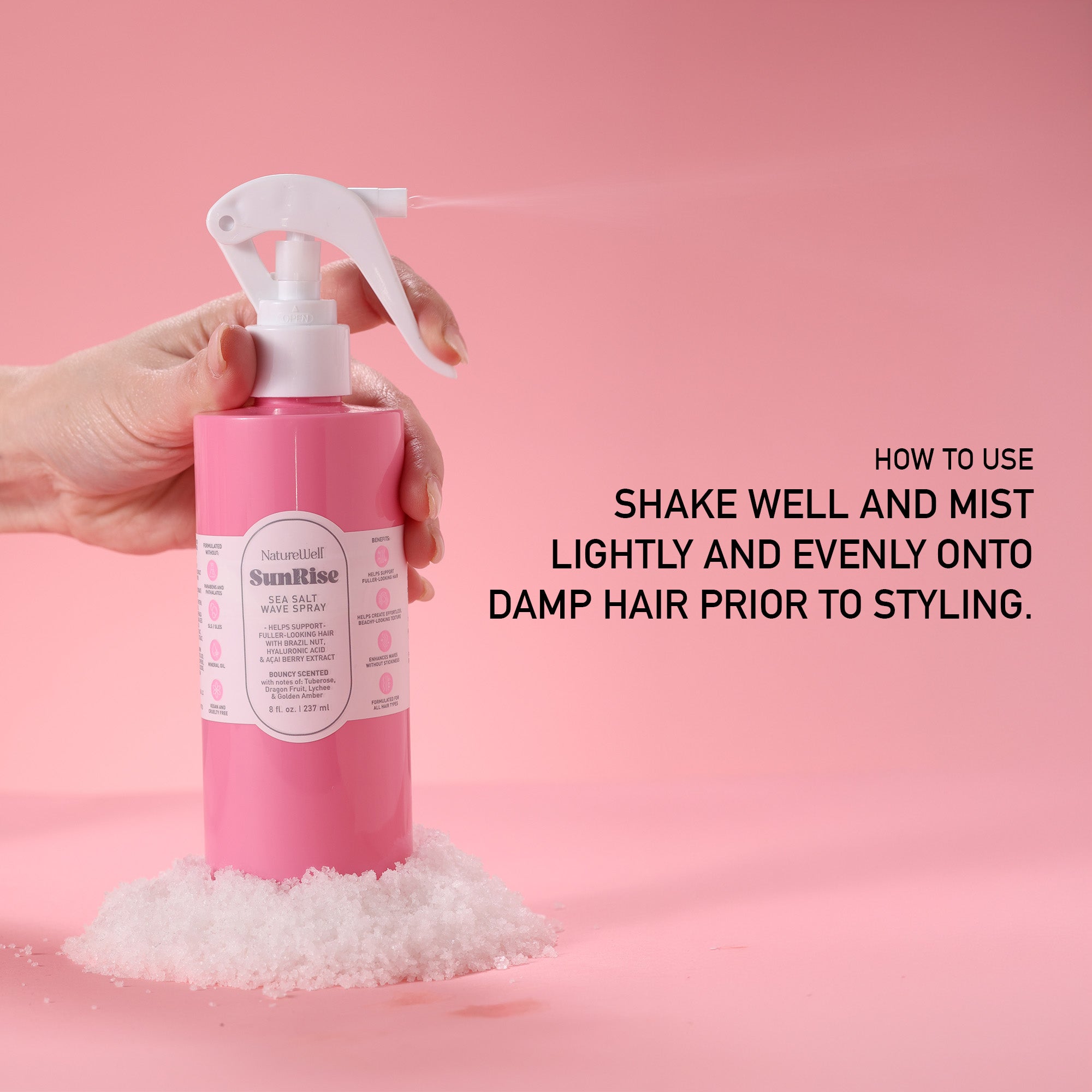 Bottle of NatureWell SunRise Sea Salt Wave Spray being misted against a pink background with instructions on how to use product